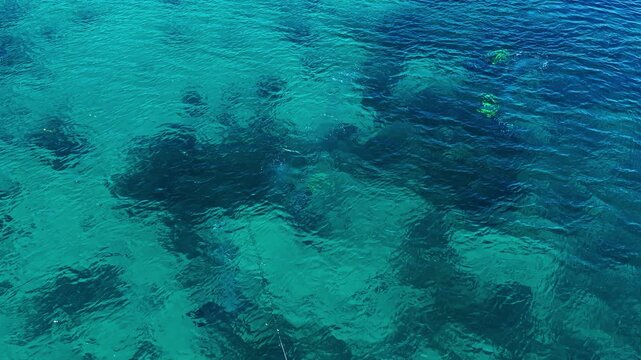 Aerial view of the clear turquoise waters at Port Barton Beach with coral reefs visible beneath the surface in Mimaropa, Philippines.