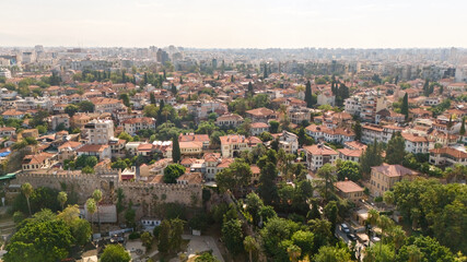 Obraz premium Aerial view of Antalya's Kaleici old town with historic walls, red tile houses, cypress trees and dense modern cityscape