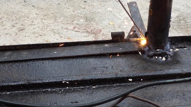 Sparks flying while welding recycled metal iron piece in workshop
