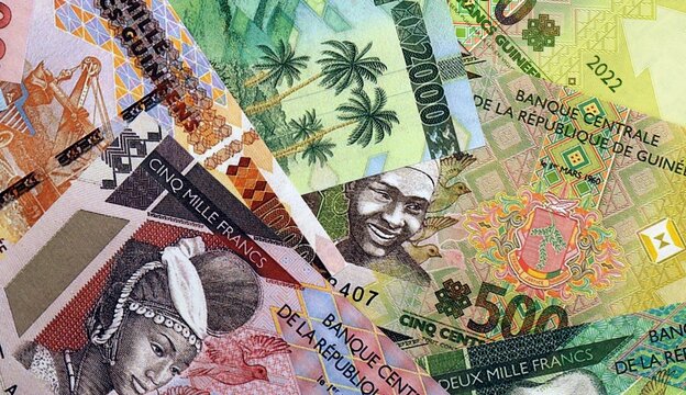 Guinean franc money bills in pile on table. Guinea GNF currency cash close up