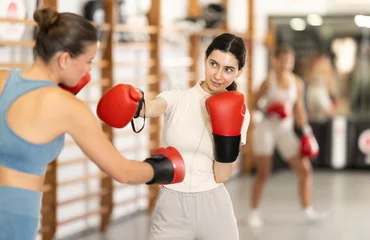 Fotobehang Onderzeeër Two women in boxing gloves sparring together in the hall. Young women during group boxing training  © JackF