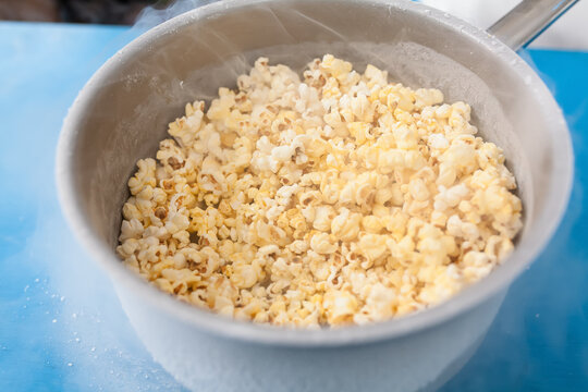Freshly Popped Popcorn in Pot: A close-up shot of a pot brimming with fluffy, golden popcorn, with a hint of steam rising, suggesting a warm and delicious treat ready to be enjoyed.