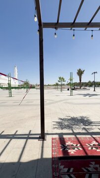 View of the white Masjid Quba from an outdoor seating area with patterned cushions in Medina.