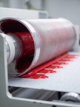 A rotary screen print cylinder laying colour onto moving cloth