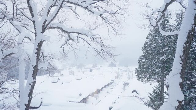 High angle view of Ouchi-juku village covered in snow during winter, traditional Japanese thatched roof houses in historic mountain town with scenic snowy landscape, Fukushima, Japan