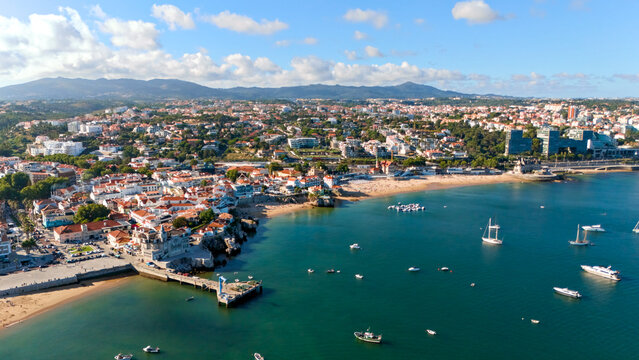 Aerial panorama of Cascais Bay with beaches, boats, historic waterfront and mountain backdrop in Portugal