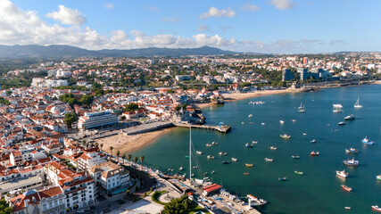 Obraz premium Aerial panorama of Cascais Bay with historic waterfront, beaches, boats and mountain-backed cityscape in Portugal