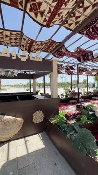 Traditional tea and coffee kiosk with outdoor majlis seating under a pergola near Masjid Quba.