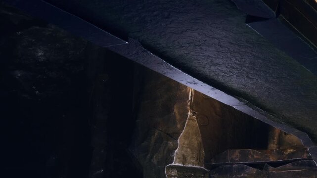 The scene shows unique rock formations inside a cave. Light filters in from above, highlighting the textures of the stone. The cave has a dark and moody atmosphere.