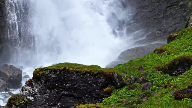 Aerial view of the powerful waterfall cascading over mossy rocks in the lush green landscape of Aurland, Vestland, Norway.