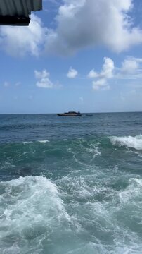 Distant boat surrounded by ocean waves &mdash; 20 seconds Distant Wooden Boat Floating Across Open Caribbean Waters Near San Andr&eacute;s Colombia with Rolling Waves, Wide Ocean Perspective and Tropical Horizon, 