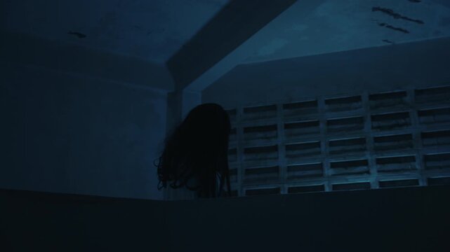 Scary halloween ghost with long black hair emerging from deep shadows creates terrifying night scene, suitable for horror films psychopath makeup or devil costumes for dead themed event.