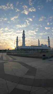 Beautiful sunrise over the white Masjid Quba and its large paved courtyard in Medina.