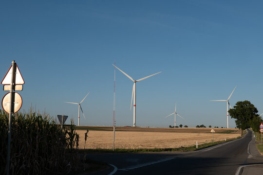 Clear blue sky above golden fields and wind turbines