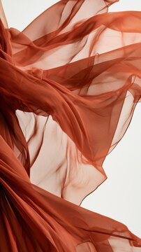 Soft terracotta chiffon fabric flows with an airy drape against a light background, creating an elegant visual display suitable for various uses.
