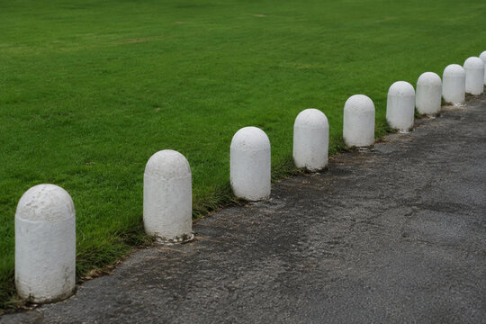 Row of white stone bollards and manicured lawn, boundary and landscaping concept