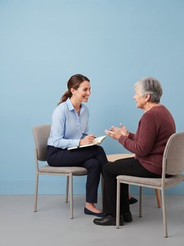 Young woman interviewing older woman in a light blue room  