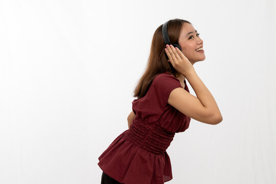 Joyful Young Woman Listening to Music while Wearing Headphones in a Bright Studio
