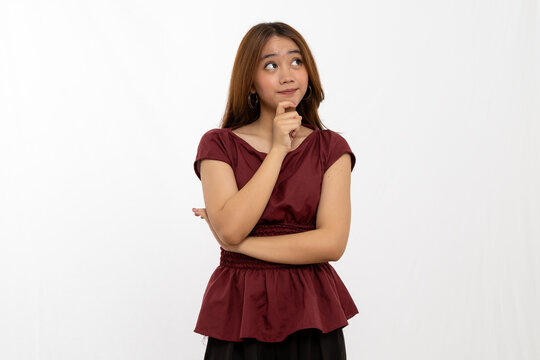 Thoughtful Young Woman With Long Hair Pondering In Maroon Top Against Plain White Background