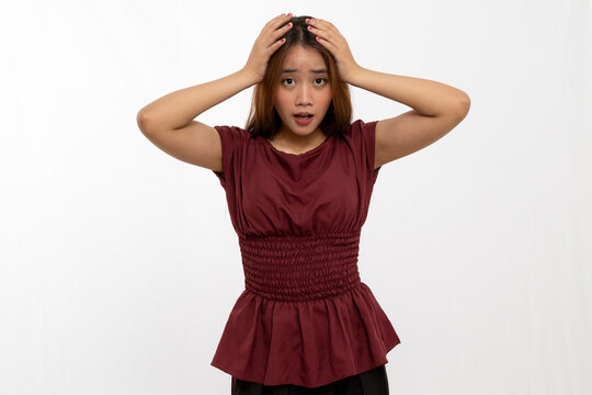 Young Woman Expressing Anxiety With Hands On Head In A Studio Setting With White Background