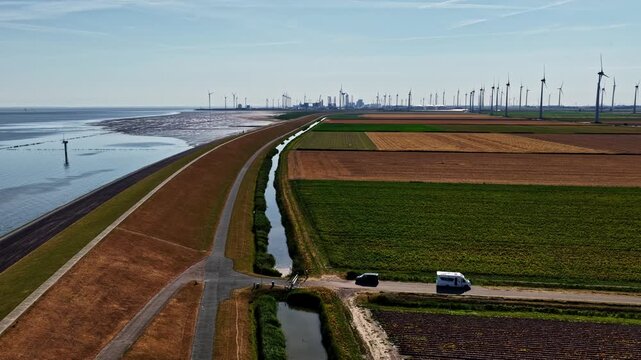 Aerial view of Eemshaven Industrial Energy Complex with wind turbines, coastal dikes, and agricultural fields in Eemshaven, Groningen, Netherlands.