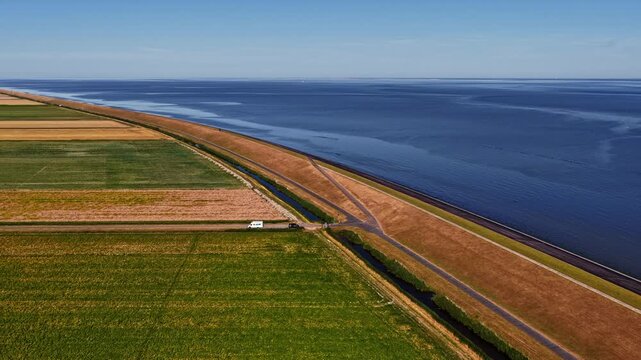 Aerial view of the coastal dike and agricultural fields bordering the Wadden Sea in Eemshaven, Groningen, Netherlands.