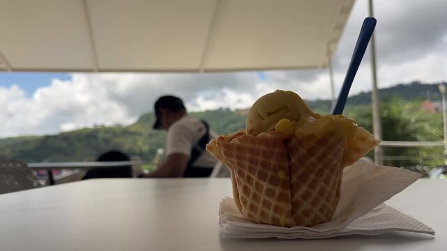 Passion fruit ice cream in waffle cone bowl at outdoor cafe terrace