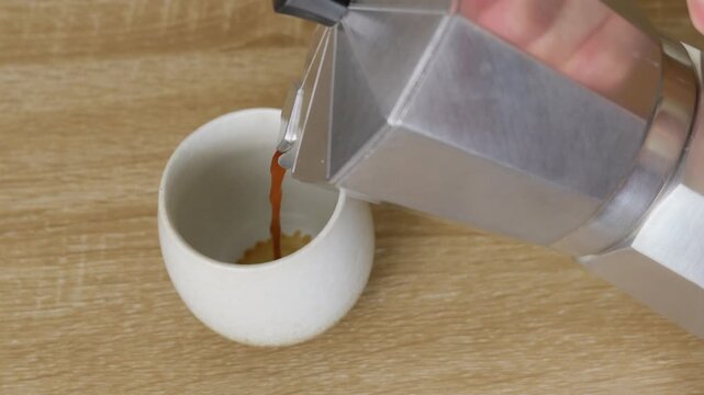 Pouring Fresh Coffee into Ceramic Cup on Wooden Table
