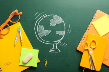 Global education and geography learning, chalk drawing of a globe on a green chalkboard with school supplies and stationery for academic study © Pixel-Shot