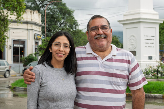 Persona mayor (hombre) abrazando a una joven mientras ambos sonr&iacute;en en un retrato en plano americano. Imagen asociada con afecto intergeneracional, bienestar, acompa&ntilde;amiento, v&iacute;nculos familiares