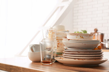 Fototapeta premium Household chores and domestic burden, stack of dirty dishes and messy glasses on a kitchen counter after a meal with leftover food residue