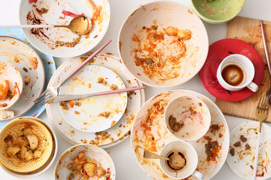 Food waste and overconsumption, dirty dishes with leftover meal scraps and empty coffee cups on a table after a large dinner party or catering event