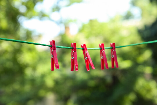 Sustainability and eco friendly living, red clothes pegs on a green washing line in a garden for laundry drying and household chores in summer