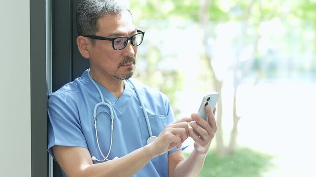 病院でスマートフォンを使う中高年の医師