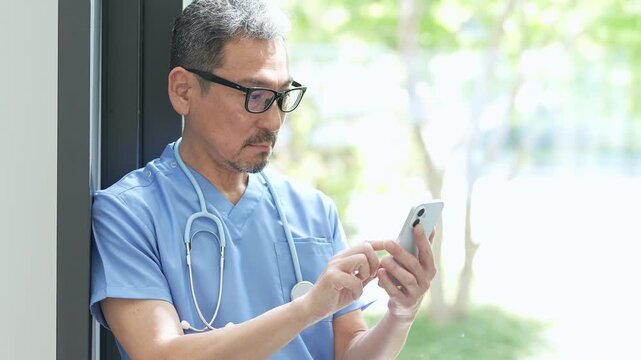 病院でスマートフォンを使う中高年の医師