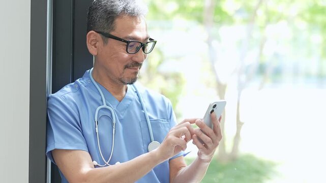 病院でスマートフォンを使う中高年の医師