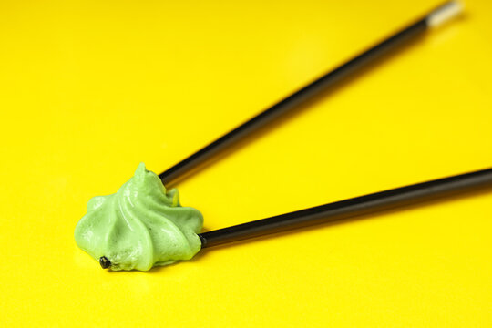 Portion of tasty wasabi with chopsticks on yellow background