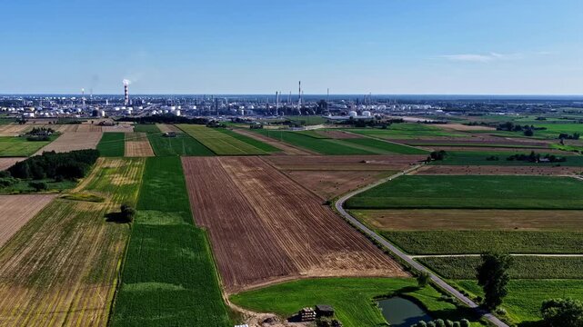 Aerial view of Orlen Plock Production Plant surrounded by vast agricultural fields and rural landscape under a clear blue sky in Plock, Mazowieckie, Poland.