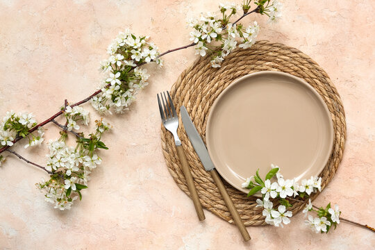 Beautiful table setting with blooming branches on beige background