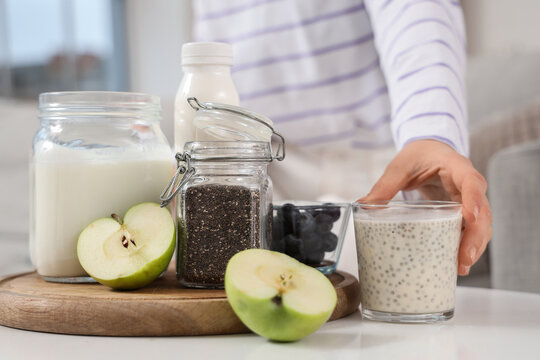 Young woman with chia seed yogurt and fruits on table at home, closeup