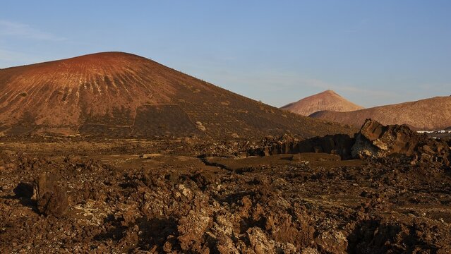 Los Vulcanos, lava landscapes with isolated volcanoes, red-brown earth, blue sky, few white clouds, Lanzarote, Canary Islands, Spain