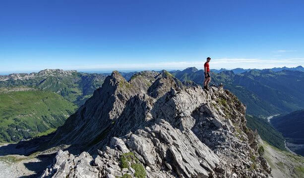 Hiker stands on rocks, hiking trail to the Hochvogel, view from the saddle at the Kreuzspitze to Allg&auml;uer High Alps, Allg&auml;u, Bavaria, Germany