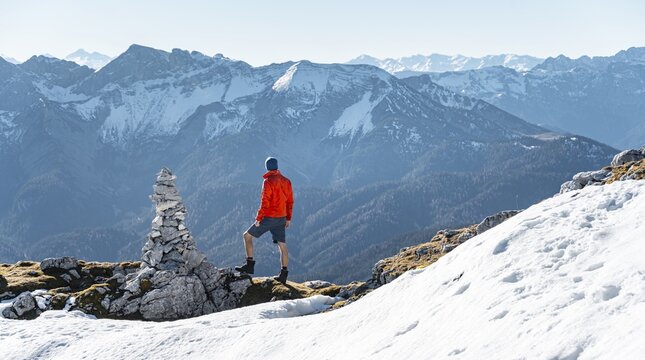 Mountaineer next to a cairn, in front of snowy mountains of the Rofan, hiking trail to the Guffert with first snow, in autumn, Brandenberg Alps, Tyrol, Austria