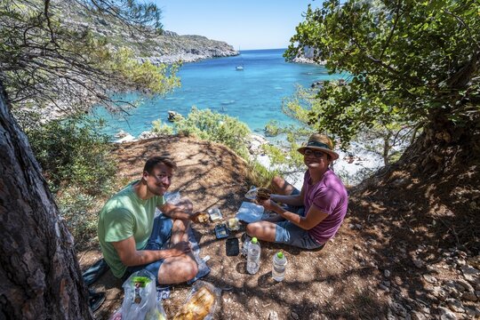 Two young men having a picnic, bay with turquoise water, Anthony Quinn Bay, Faliraki, Rhodes, Dodecanese, Greece