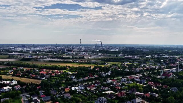 Aerial view of the ORLEN Plock Production Plant with industrial chimneys and storage tanks surrounded by residential areas and green fields in Plock, Wojewodztwo mazowieckie, Poland.
