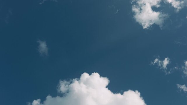 Large expanse of blue sky in the center with small clouds around the edges