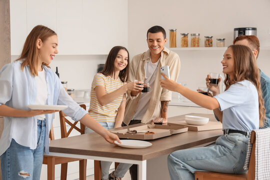Group of young friends eating pizza at home party