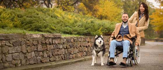 Accessibility and inclusion, happy man in wheelchair with partner and husky dog walking in autumn park for lifestyle and disability support © Pixel-Shot