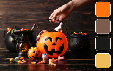 Naklejka premium Halloween celebration and trick or treat tradition, child hand holding pumpkin bucket with candy and spooky sweets on dark wooden background