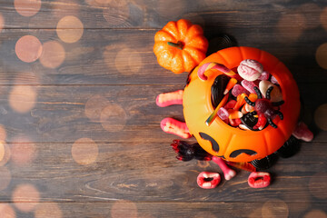 Naklejka premium Halloween celebration and trick or treat tradition, pumpkin bucket filled with spooky gummy candies and sweets on a rustic dark wooden background